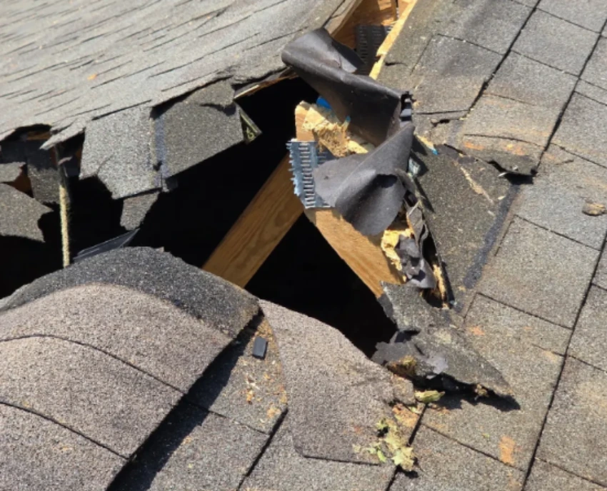 Storm damage roof hole with broken shingles and exposed decking in Annapolis Maryland